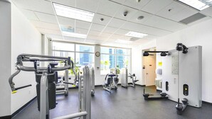 Ein Fitnessstudio mit verschiedenen Trainingsgeräten, großen Fenstern und einem modernen, aufgeräumten Design.