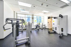 Ein Fitnessstudio mit verschiedenen Trainingsgeräten, großen Fenstern und einem modernen, aufgeräumten Design.