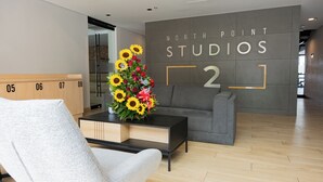 Un interior moderno con un sofá, una silla, una mesa de centro con un arreglo floral y una pared con el texto "NORTH POINT STUDIOS 2".
