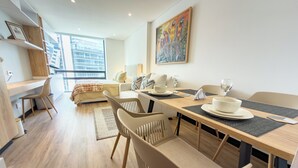 Una sala de estar moderna con comedor, que incluye una mesa de madera, sillas y un sofá.
