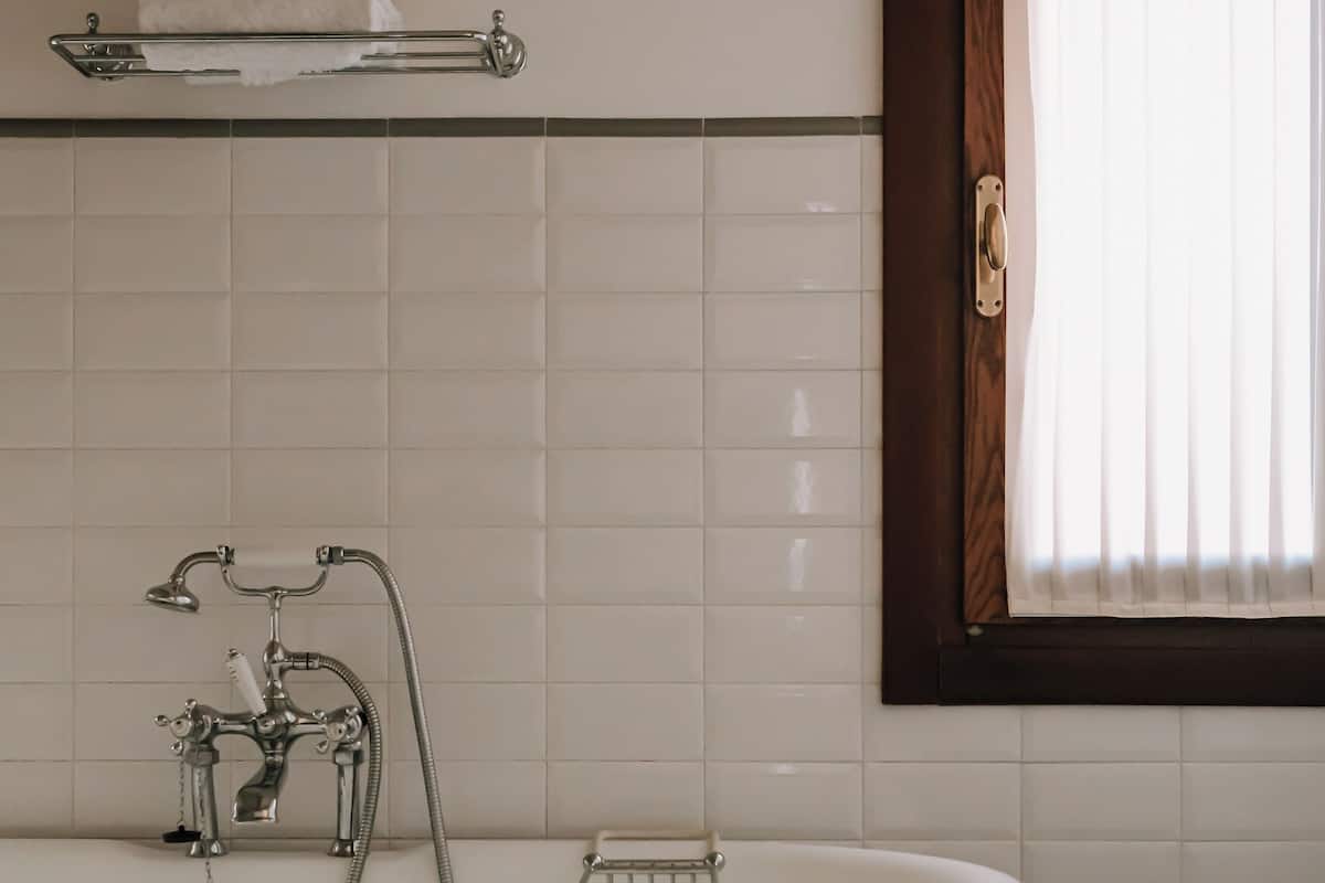 Une salle de bain avec une baignoire sur pieds, un porte-serviettes et une fenêtre avec des stores.