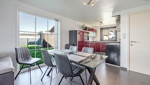 Una cocina moderna con armarios rojos, una mesa de comedor de cristal y sillas.
