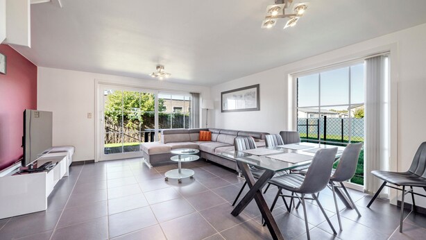 Una sala de estar moderna con un sofá modular, una mesa de comedor de vidrio y un televisor a la izquierda.