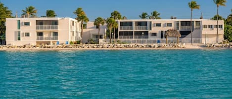 Um hotel à beira-mar com vários andares, varandas e área de piscina.