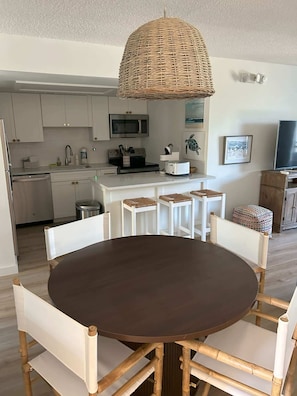 A modern kitchen with white cabinets, a microwave, and a toaster. There is a dining area with a round table and chairs. - Keys Coastal Escape Pool Beach Ocean U20 (Marathon)