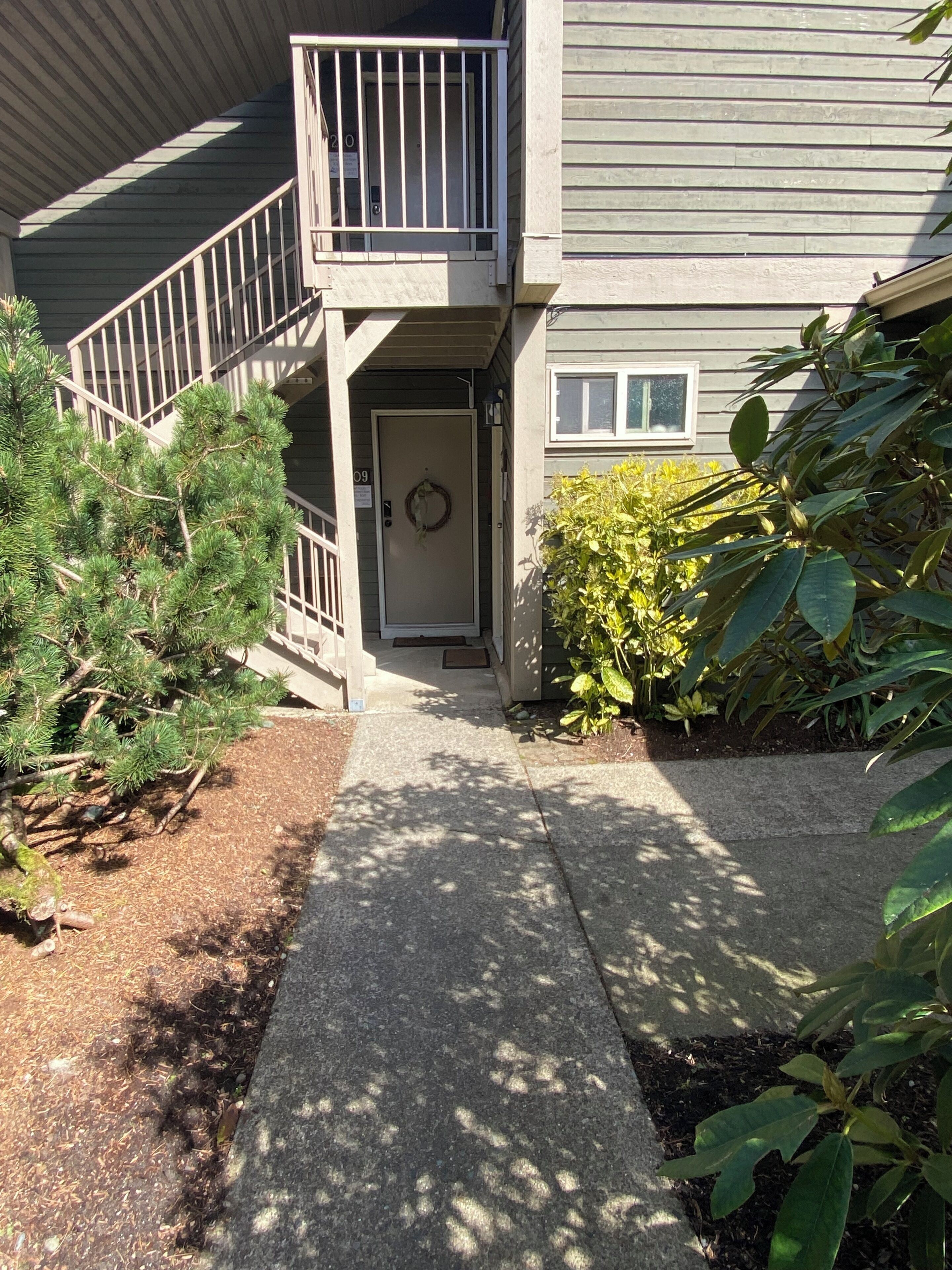 A residential building with a front entrance, a small porch, a staircase, and a mailbox.