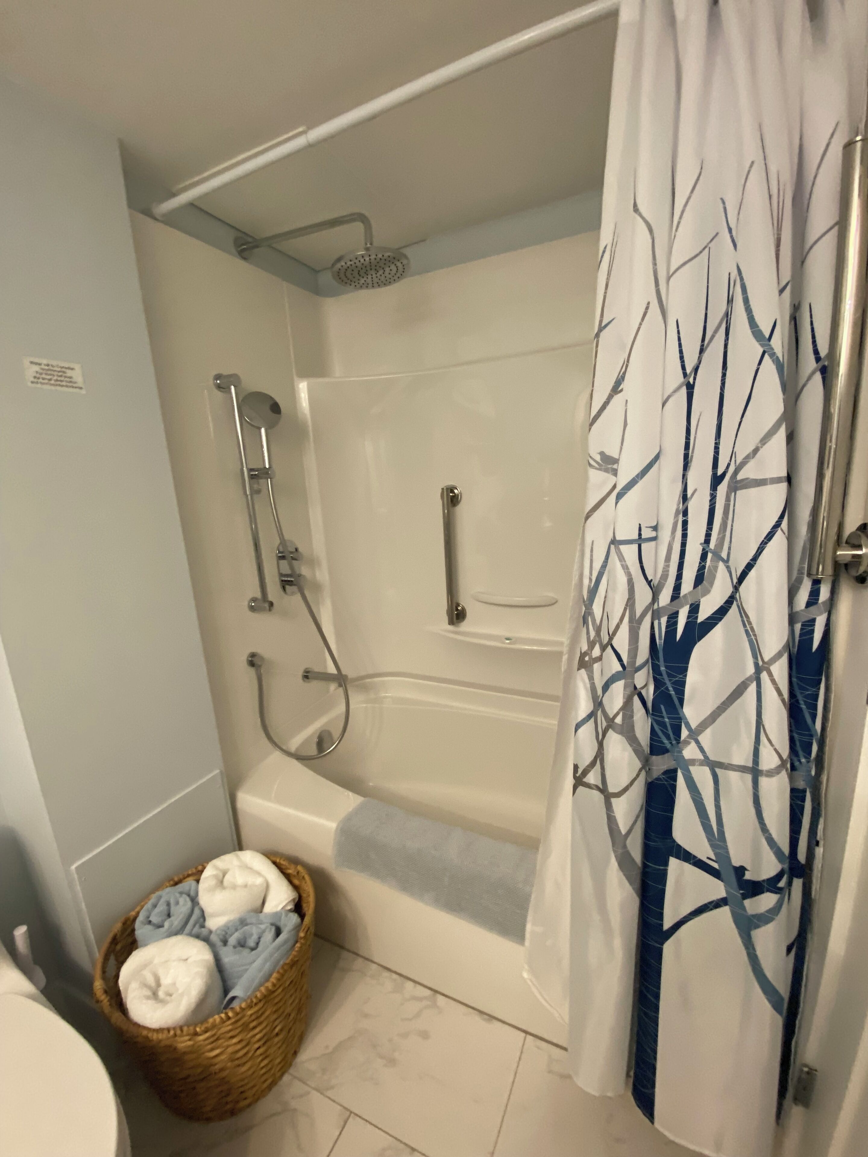 A bathroom with a bathtub, shower, and a wicker basket with towels.