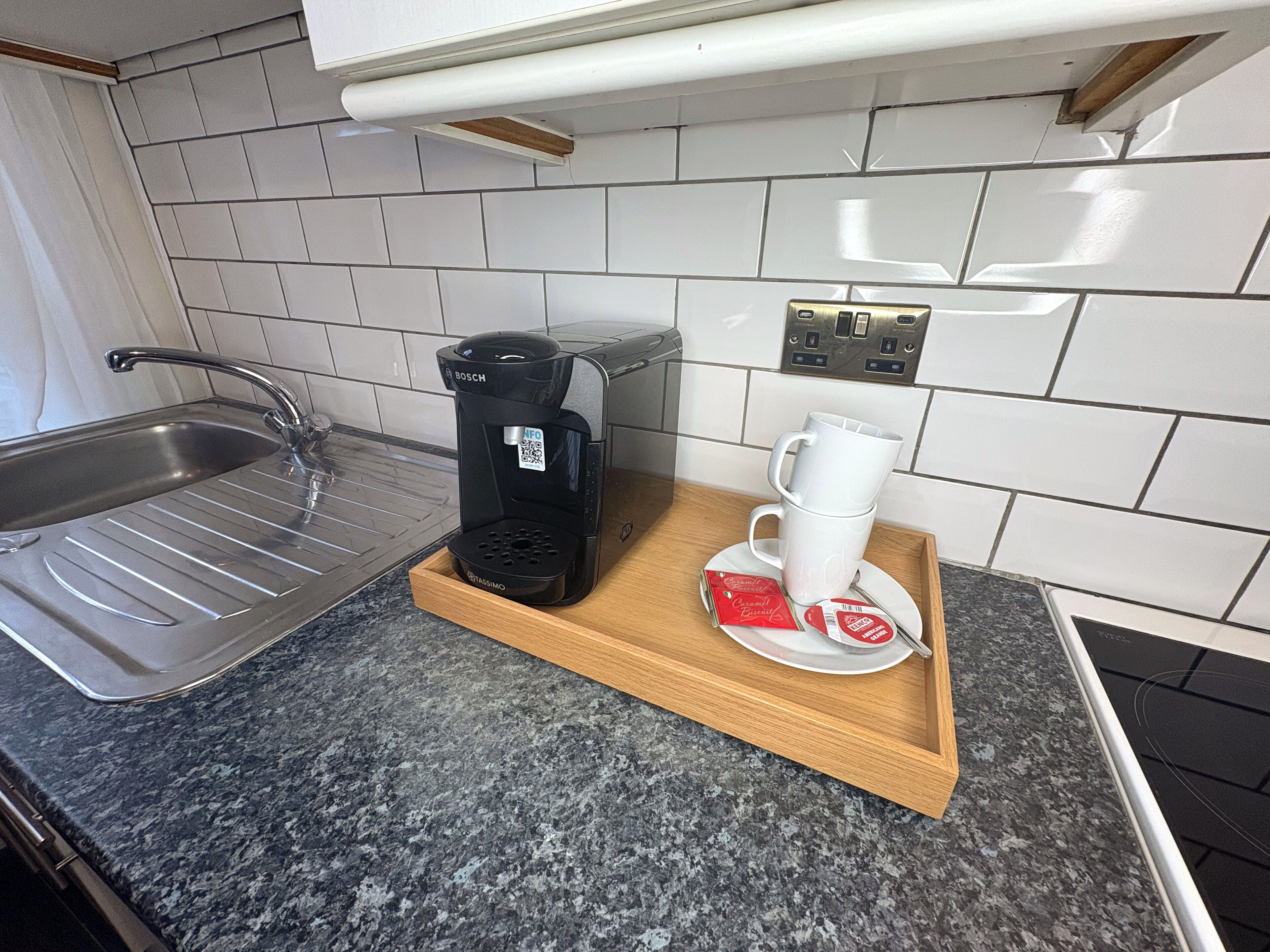 Eine Küche mit Kaffeemaschine, Tasse und Tablett mit Kaffeekapseln.