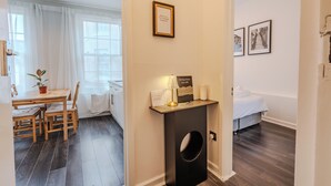 Une chambre d’hôtel avec un lit, une petite table et des chaises, un radiateur fixé au mur et un panneau d’accueil encadré.