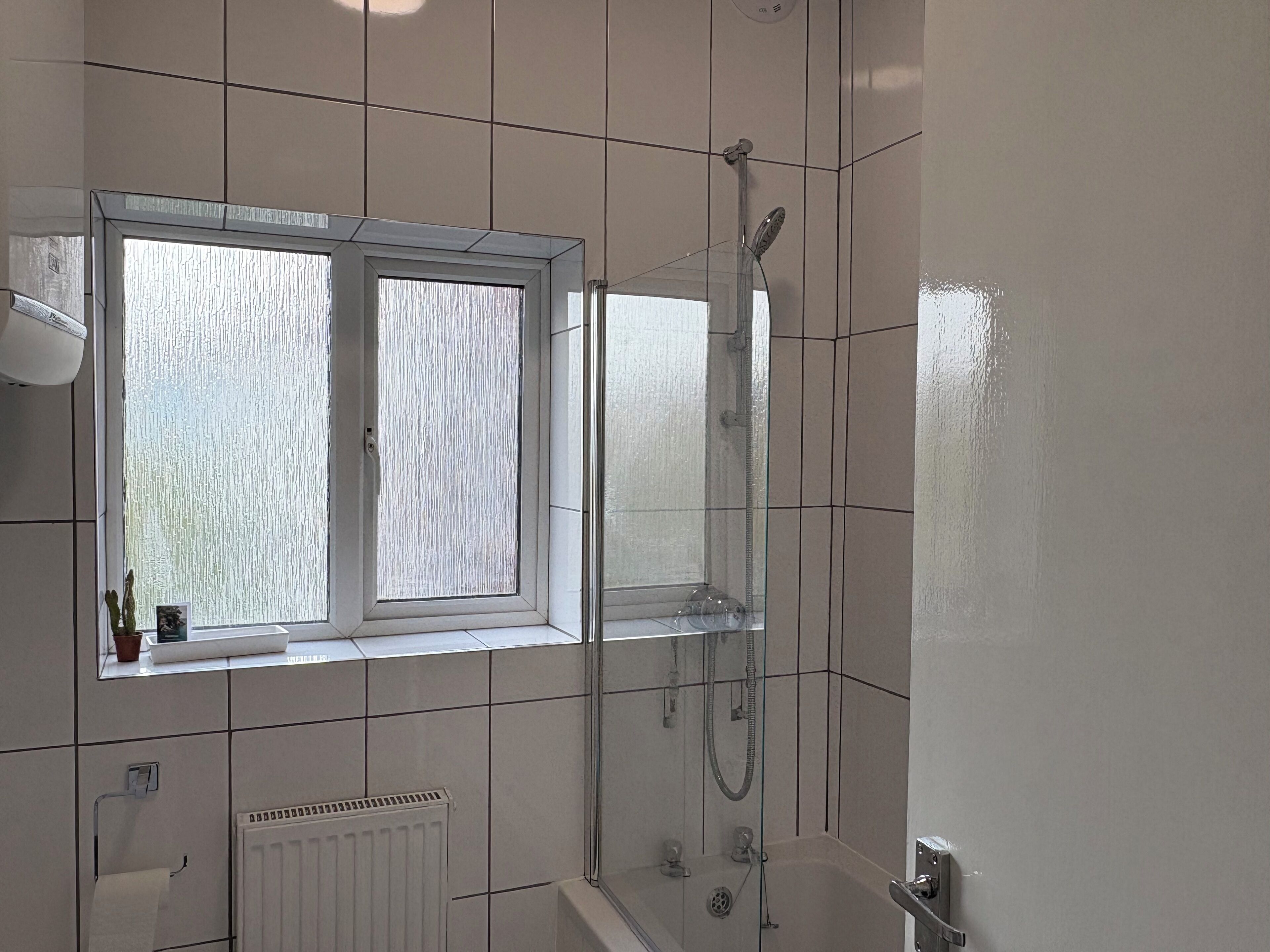 Ein modernes Badezimmer mit Fenster, Dusche und Badewanne.