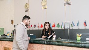 Una mesa de recepción con relojes, banderas y un cartel que indica 'TASHKENT'.