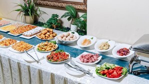 Una mesa de buffet con diversos platos, incluyendo ensaladas, carnes y pasteles.