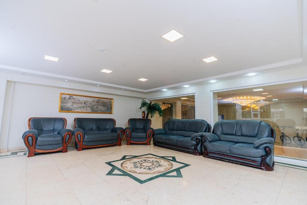 A lobby with four sofas, a patterned rug, and a framed picture on the wall.