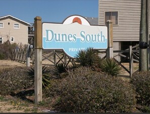 A sign for Dunes South Private labeled with a sun and beach theme.