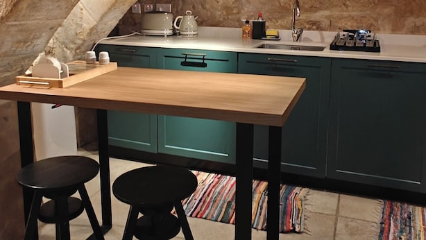 A kitchen with a wooden table and two stools, a sink, and teal cabinets. - Traditional Maltese 1BR Home - Valletta (Valletta)