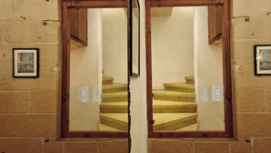 A mirrored view of a staircase with wooden steps and a white wall. - Traditional Maltese 1BR Home - Valletta (Valletta)