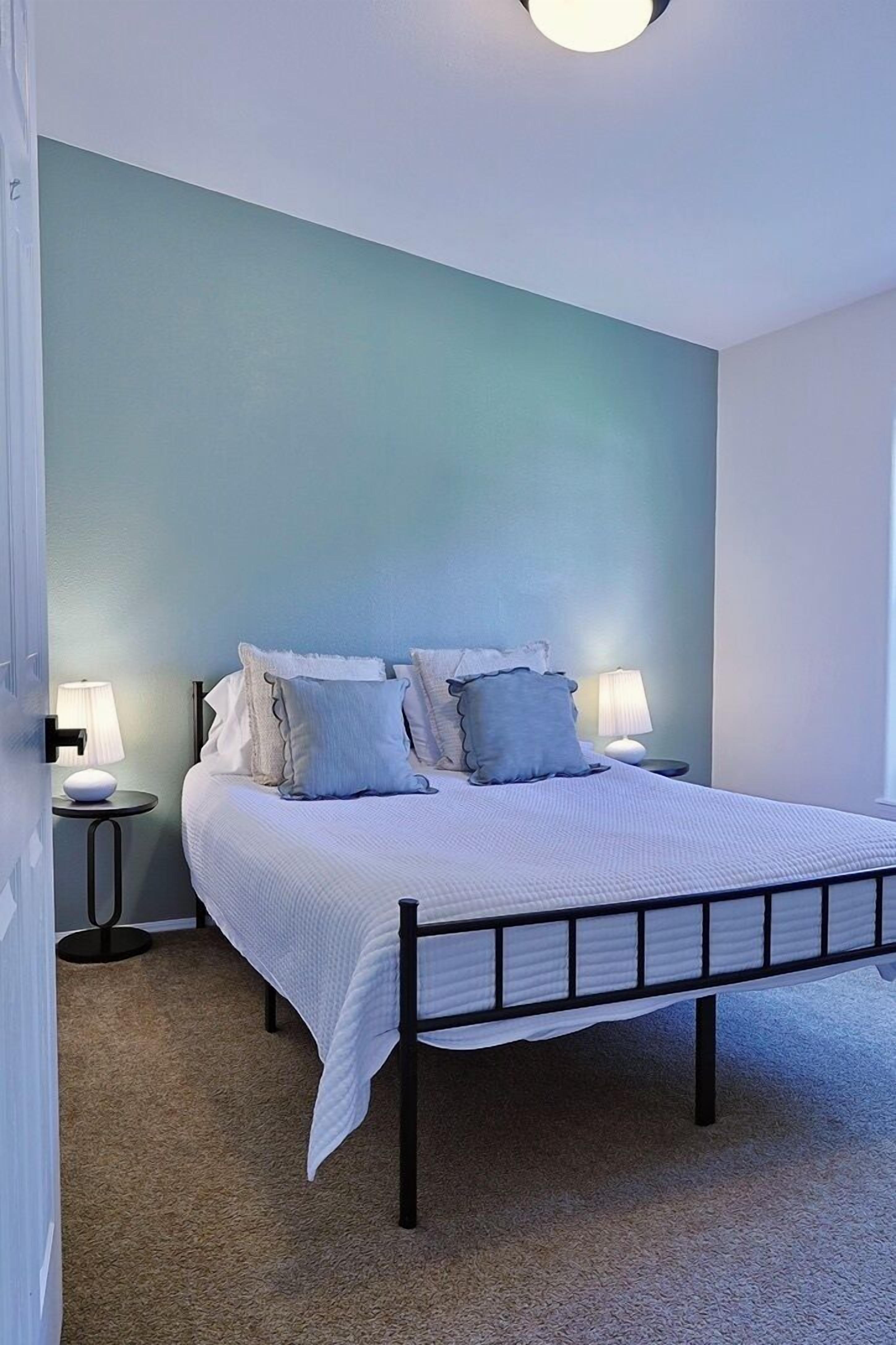 Ein Schlafzimmer mit einem Bett, zwei Nachttischen und einer Wandlampe.