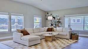 A spacious living room with a large L-shaped sectional sofa, a wooden coffee table, and a checkered rug. - Happy's Hideaway w/ Hot Tub, Sleeps 12, Downtown! (Ellensburg)
