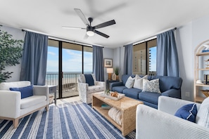 A modern living room with a balcony, a ceiling fan, and a view of the ocean. - Seaside Beach & Racquet 3501 (Orange Beach)
