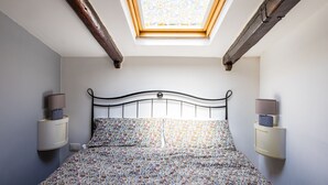 Un dormitorio con tragaluz, una cama con ropa de cama floral y lámparas de noche.
