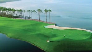 A golf course with a water body, sand bunkers, and trees. - Epic! Ocean views! Sleeps 20! Pool! Golf cart! (Destin)