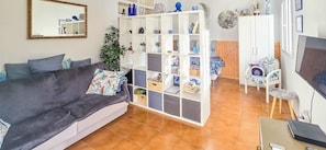 A living room with a sofa, a white shelving unit, a plant, and a TV. - Lovely Apartment in Beautiful Mogan (Los Pasitos)