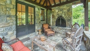 A stone exterior with a wooden ceiling, a fireplace, and wicker furniture. - AHMA Cottage 2 (Canton)