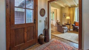 A wooden door with glass panels, a rug, and a vase with sticks. - AHMA Cottage 2 (Canton)