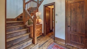 A wooden staircase with a lamp and a dresser, leading to a door. - AHMA Cottage 2 (Canton)