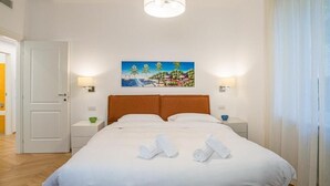 A hotel room with a bed, two bedside tables, a painting on the wall, and a door to the left. - Central Cernobbio - Modern Apartment (Cernobbio)