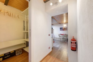 A hallway with white walls, wooden flooring, and a fire extinguisher mounted on the wall.