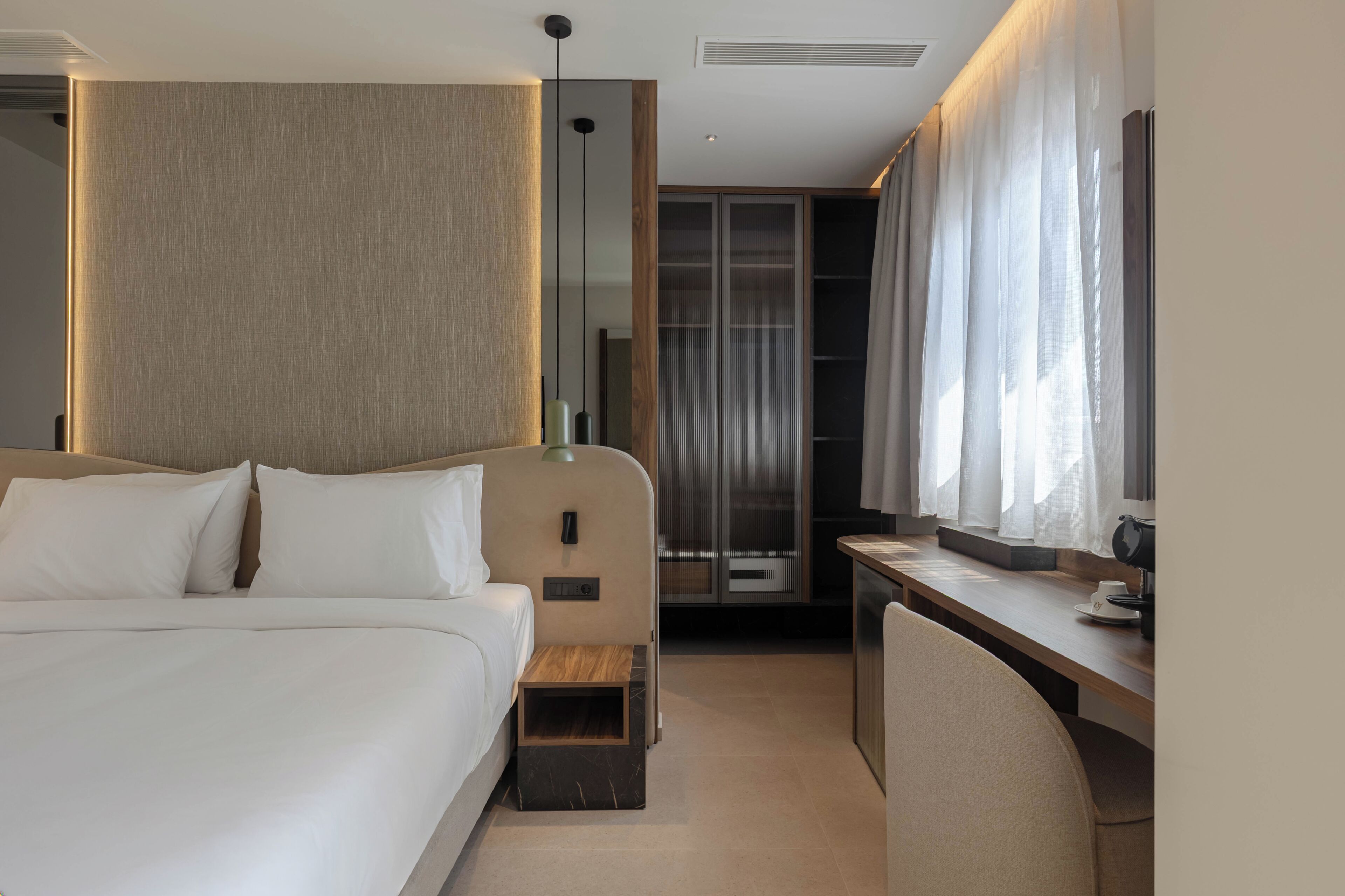 A modern hotel room with a large bed, a desk, and a walk-in closet.