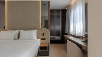 A modern hotel room with a large bed, a desk, and a walk-in closet.