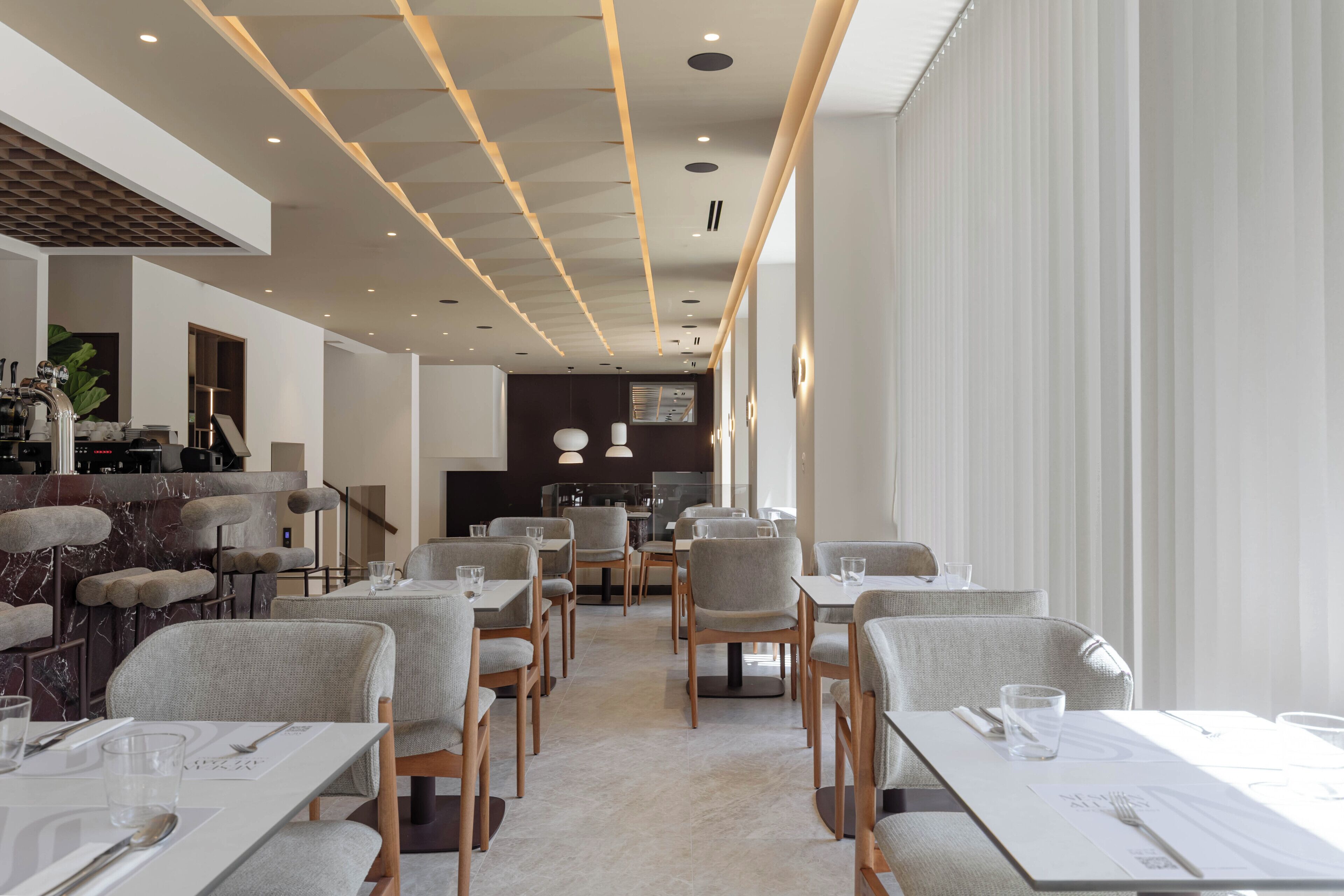 Un restaurant moderne doté d’un long comptoir, de nombreuses tables et de chaises.