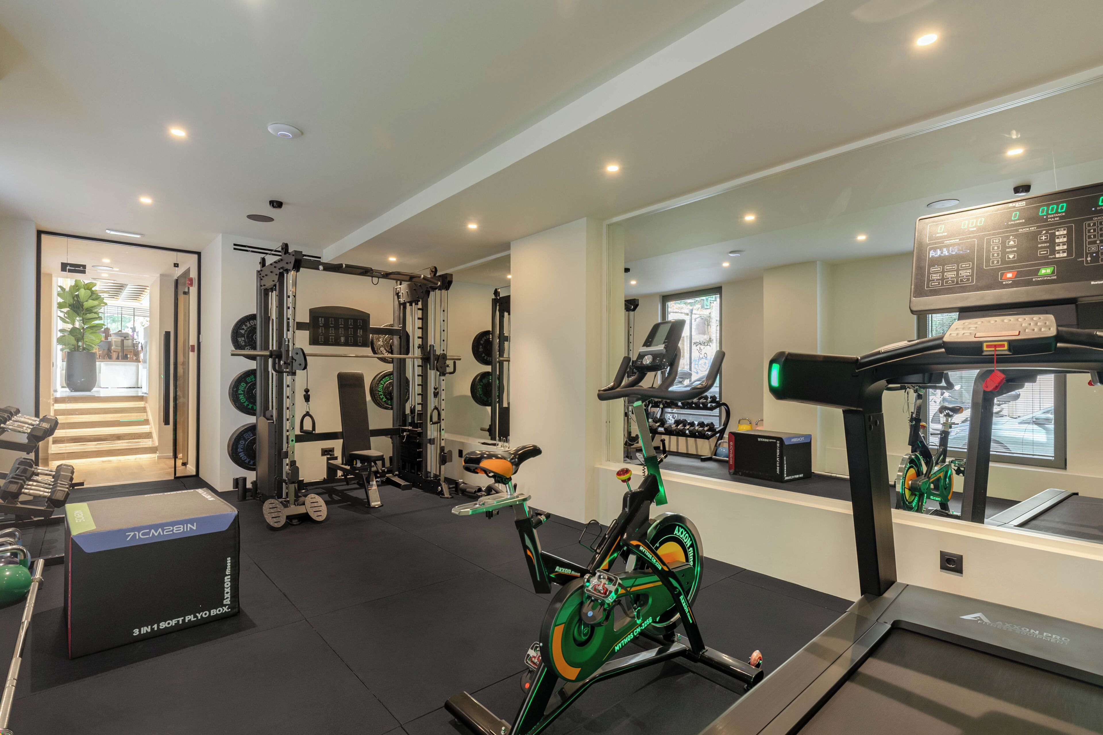 A gym with various exercise equipment, including a treadmill, stationary bike, and weightlifting area.
