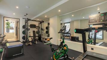 A gym with various exercise equipment, including a treadmill, stationary bike, and weightlifting area.