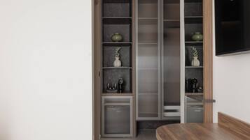 Un interior moderno con una mesa de comedor de madera, una estantería empotrada con objetos decorativos y un televisor de pantalla plana grande montado en la pared.