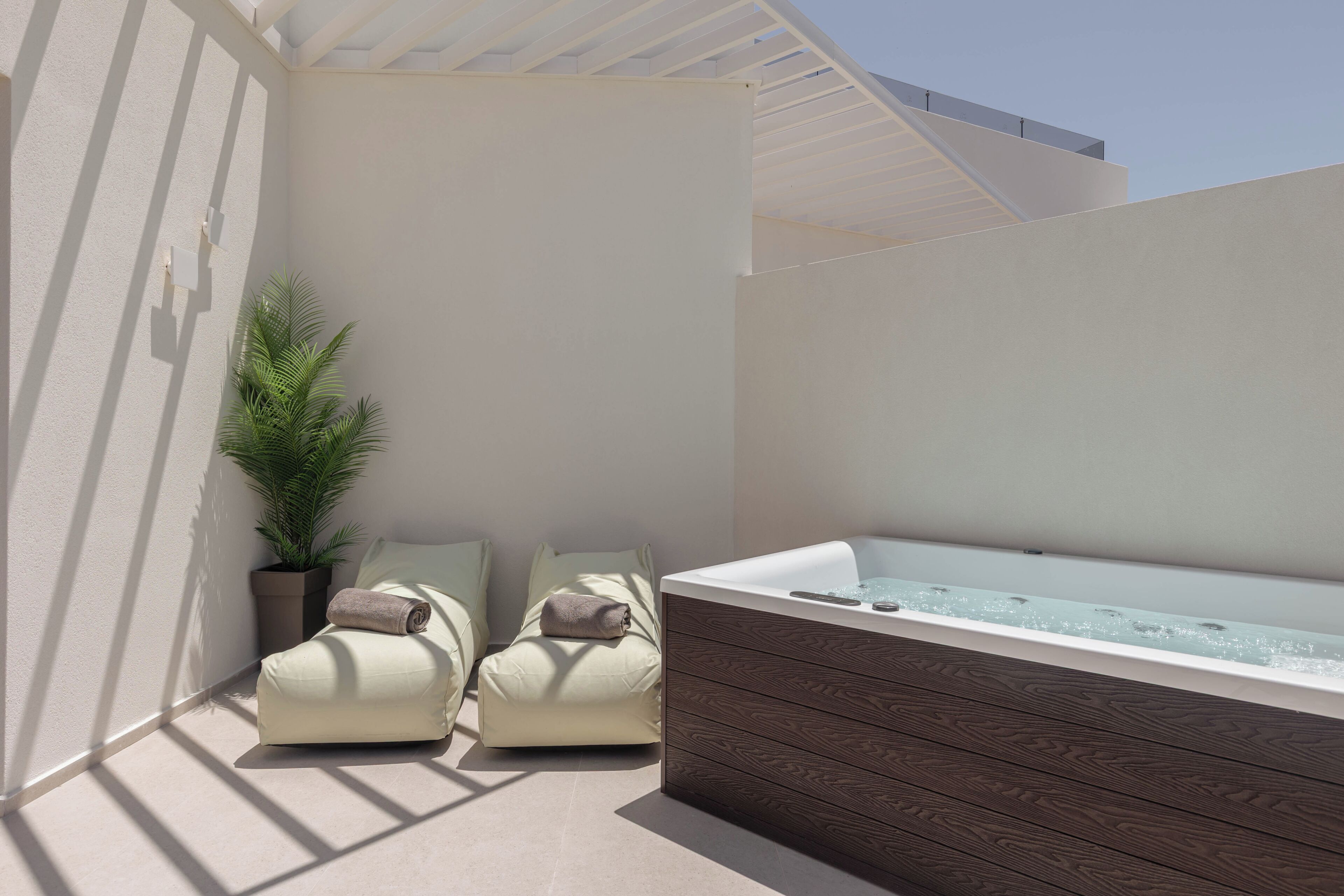 A spa area with a hot tub, two lounge chairs, and a potted plant.