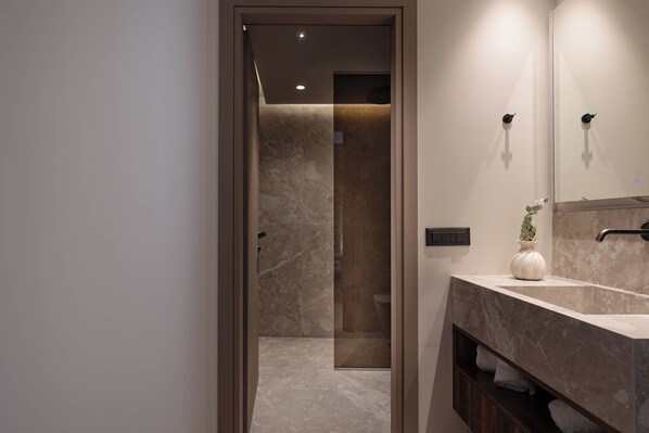 Un baño moderno con lavamanos de mármol, espejo y cabina de ducha.