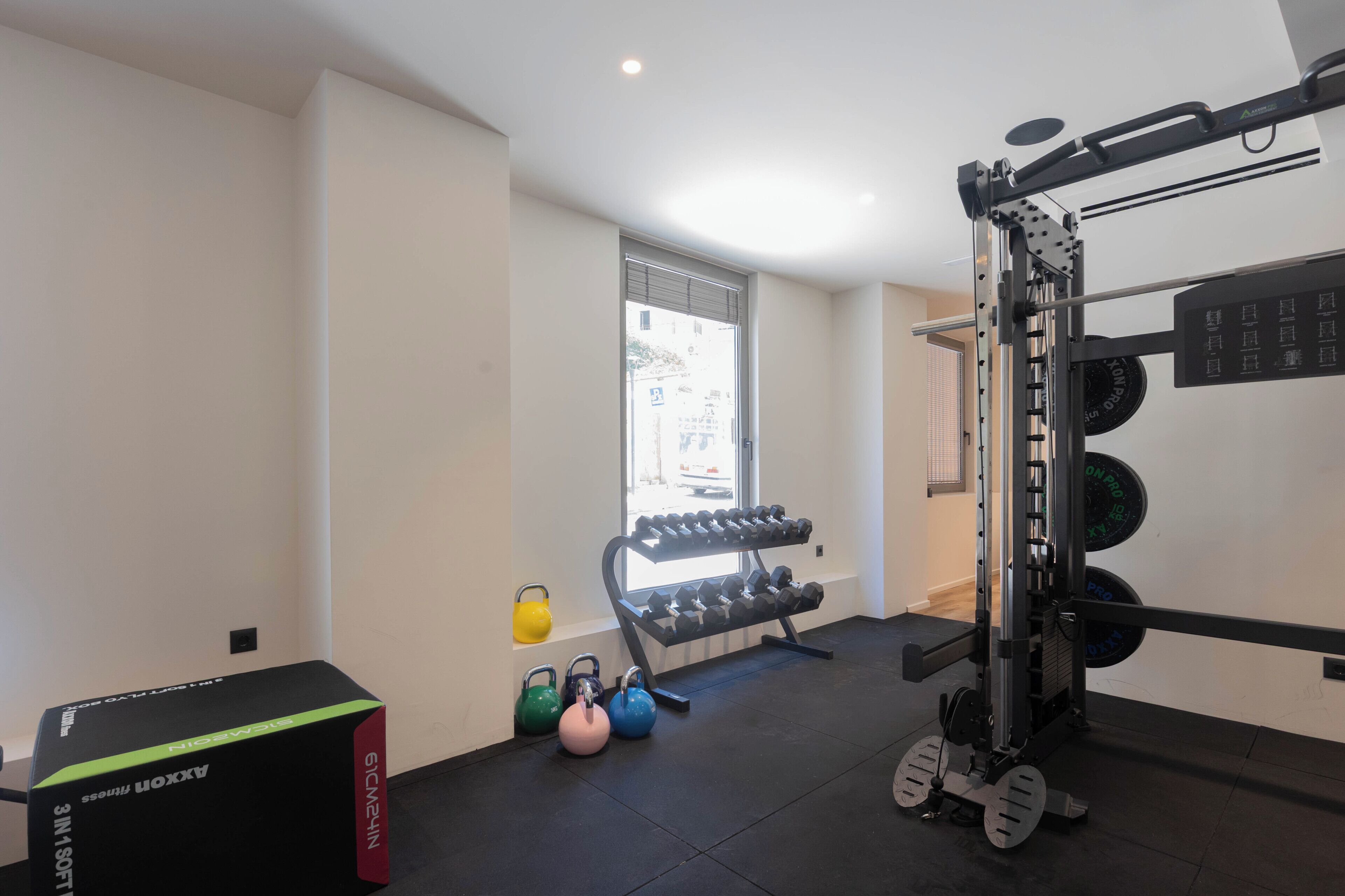 Ein Fitnessraum mit Hantelgestell, Kettlebells und Kurzhanteln.