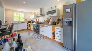 A modern kitchen with white cabinets, a stainless steel refrigerator, and a microwave. - Villa with pool 2.5km from Saint-Tropez (Gassin)