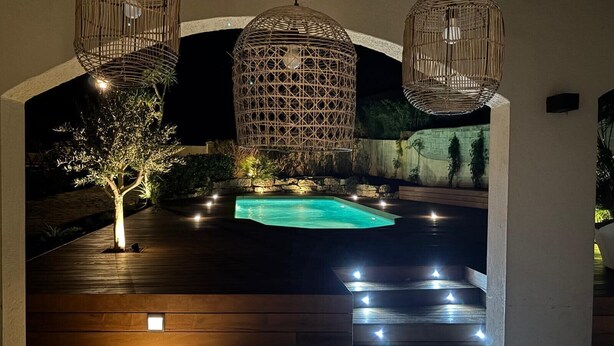 An outdoor pool area with a wooden deck, a small tree, and three wicker hanging lamps. - Villa with pool 2.5km from Saint-Tropez (Gassin)