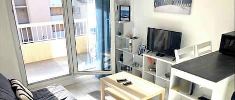 A living room with a sofa, a coffee table, a TV, and a bookshelf.