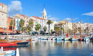 A marina with boats docked, a church with a bell tower, and colorful buildings along the waterfront. - Spacious new studio apartment, close to the sea (Sanary-sur-Mer)