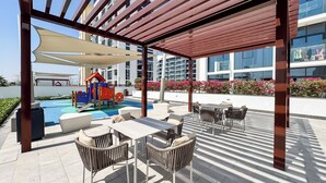 Eine Dachterrasse mit Außenmöbeln, einem Spielbereich für Kinder und einem Pool.