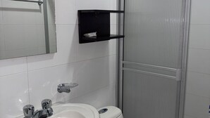 Une salle de bain avec un lavabo blanc, des toilettes et un espace douche.