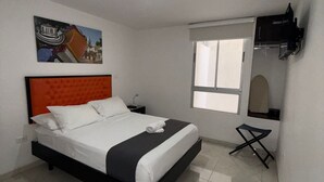 Une chambre à coucher moderne avec un lit, une petite table, une fenêtre et un téléviseur fixé au mur.