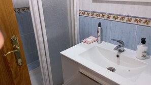 Ein Badezimmer mit einem weißen Waschbecken, einem Spiegel und einer Tür mit Messinggriff.