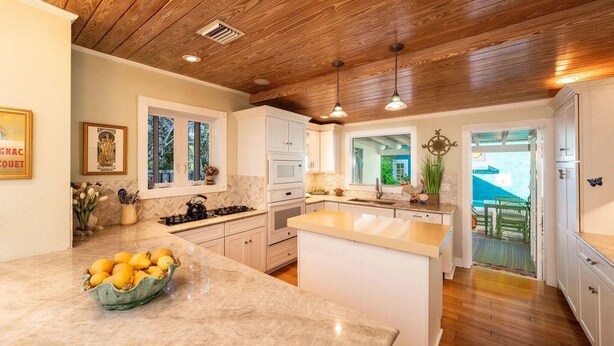 A kitchen with wooden ceiling, white cabinets, a central island, and a view to the outside. - Monthly rental-1 level, 4-bed, 3 bath, quiet home, private sunny pool, parking (Key West)