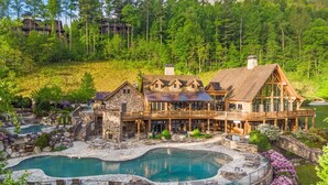 A large lodge with a pool, stone walls, and a forest backdrop. - Best of Bear Lake | Pool • Golf • Lake & Mtn Views (Tuckasegee)
